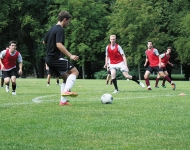 The men's soccer team practicing in red jerseys.